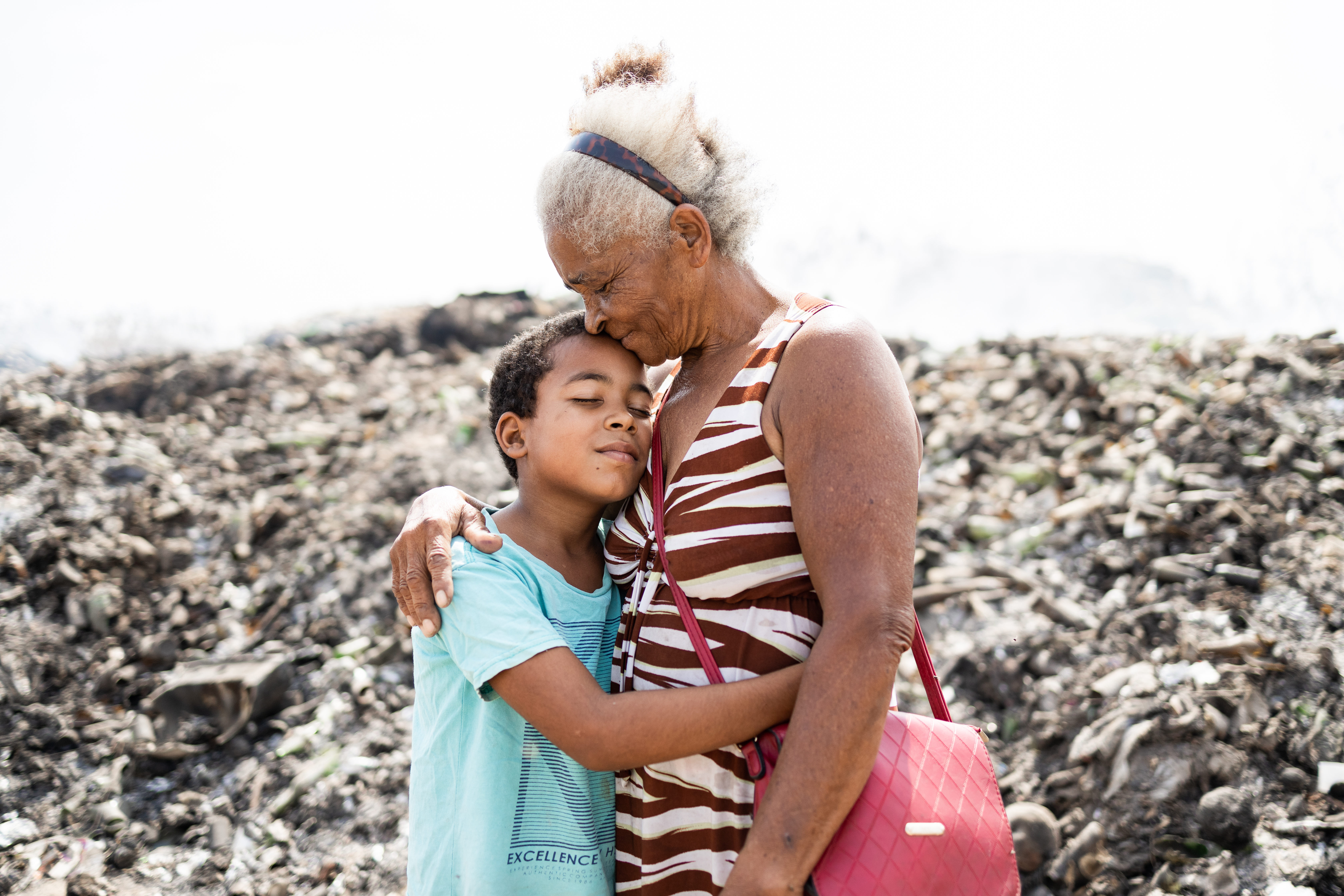 A young boy and an older woman hug each other with their eyes closed.